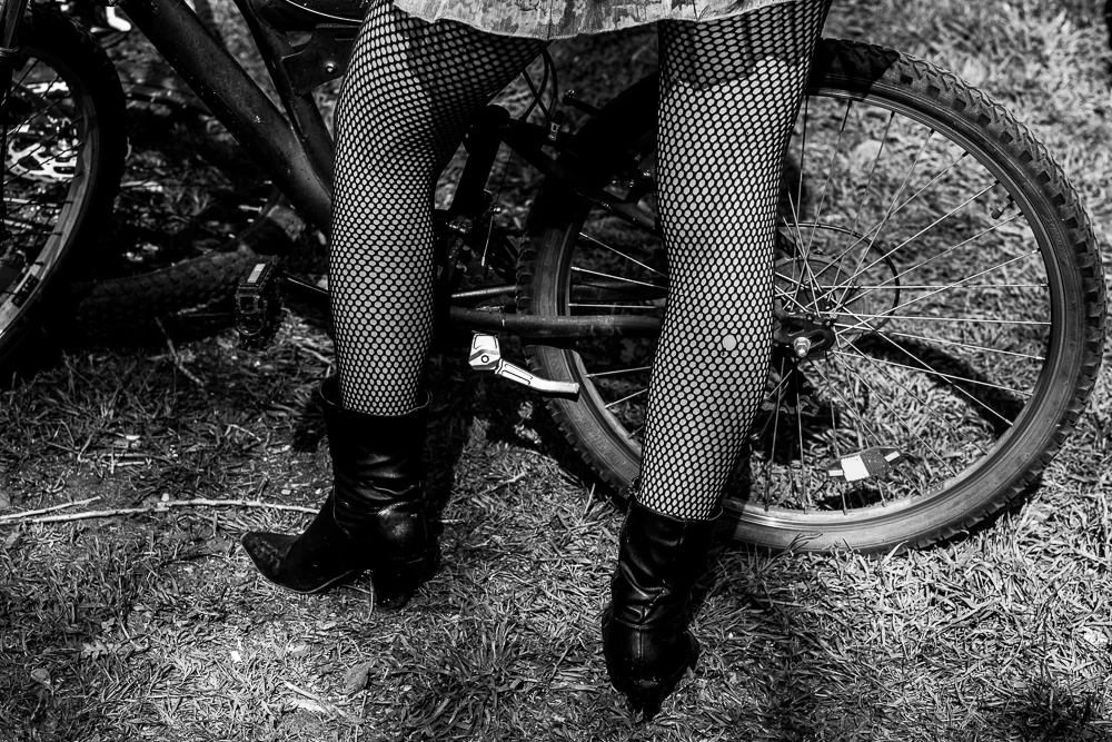 Legs and a bicycle wheel in dappled light. Photograph by Adelina Persa.